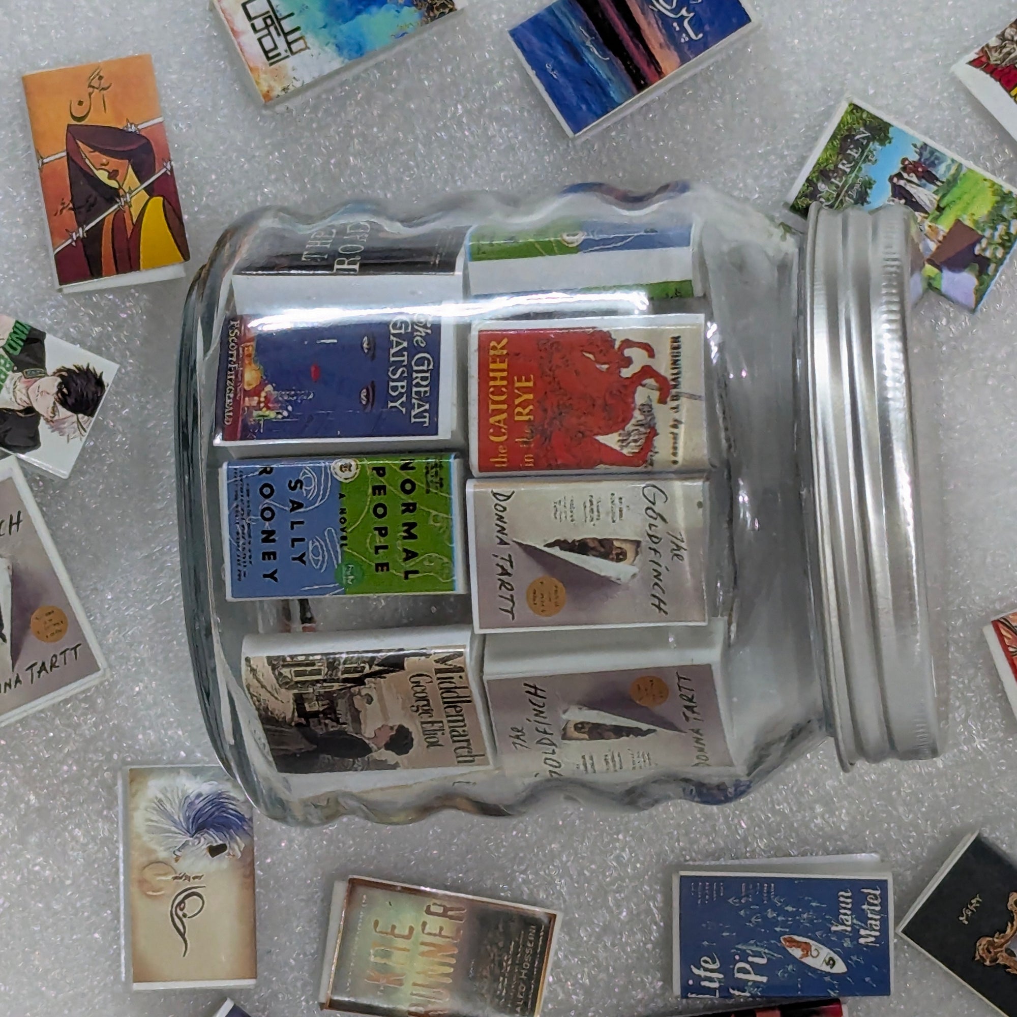 Jar filled with books on a textured surface with scattered books around